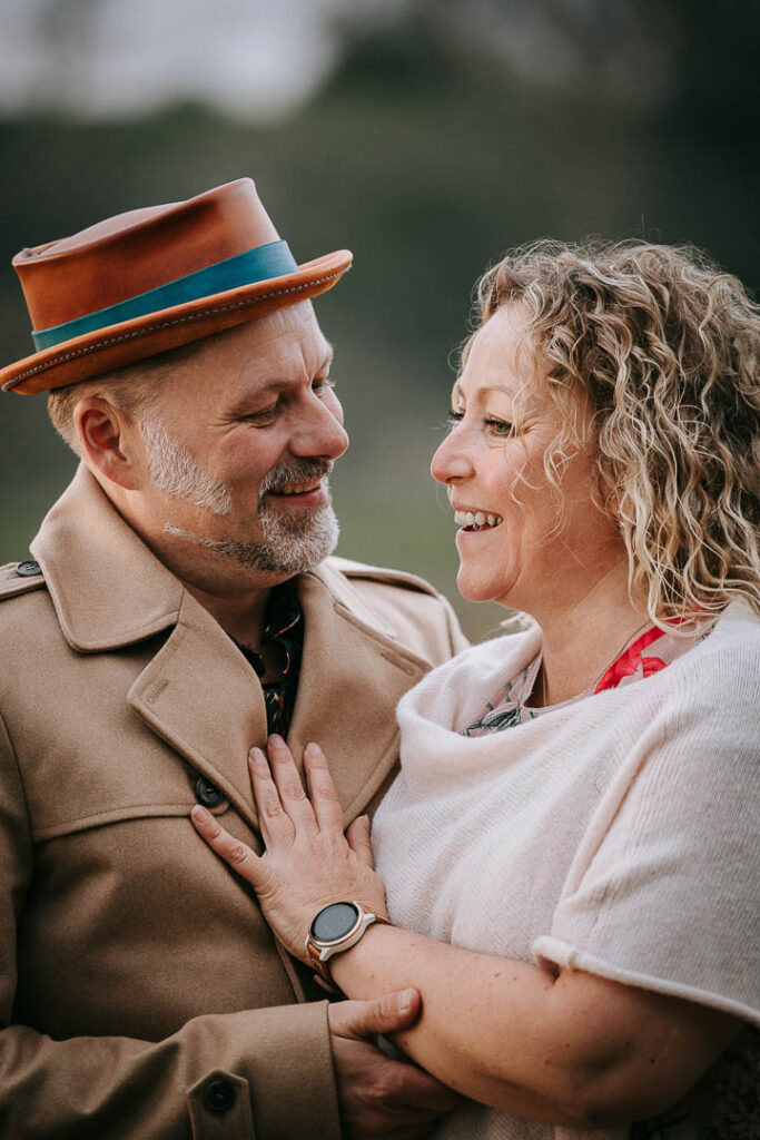 Udendørs parfotografering – par står tæt og smiler, fotograferet af Zoey Elinor.