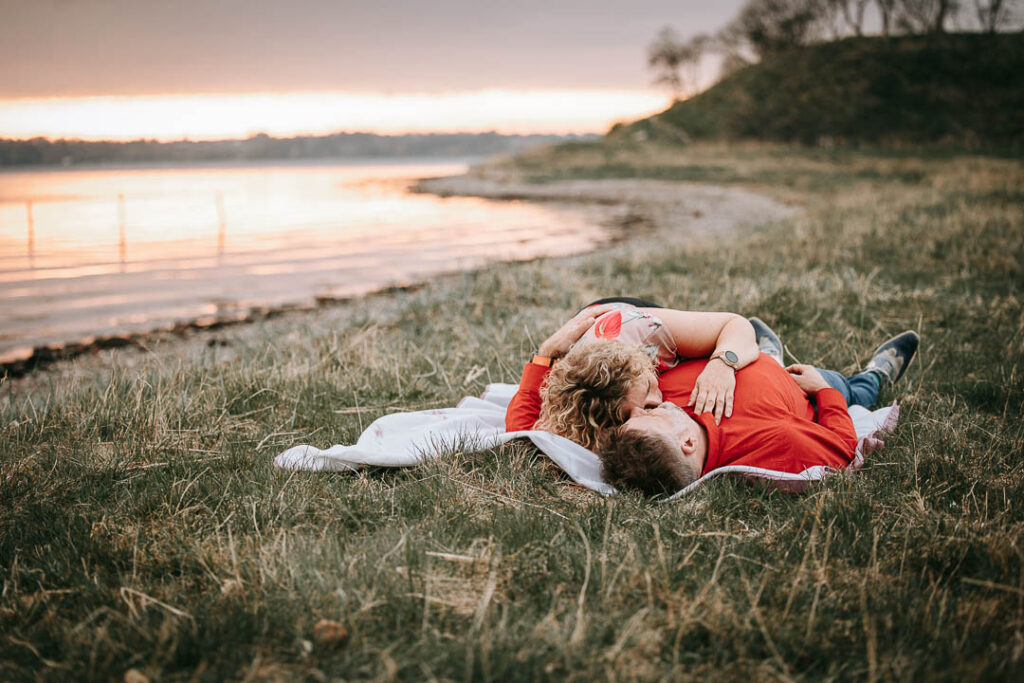 Parfotografering ved vandet på Hindsgavl Slot – par ligger sammen ved kysten.