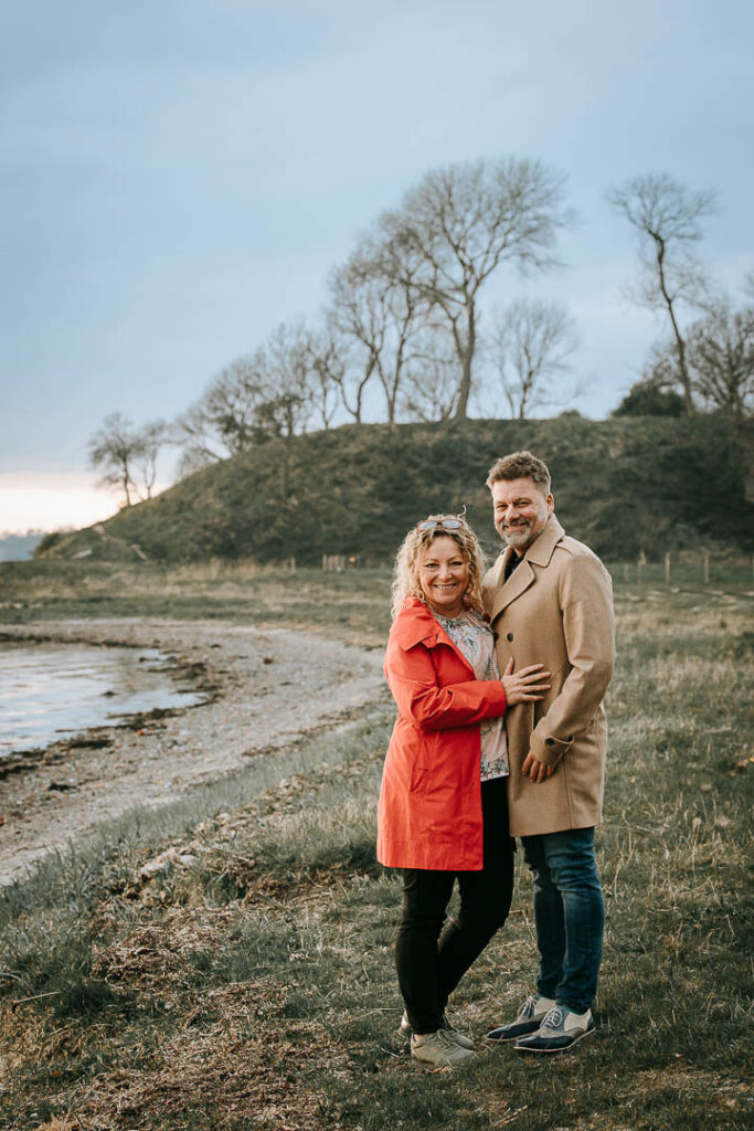 Udendørs parfotografering ved Hindsgavl Slot – par står ved vandkanten i landskabet.