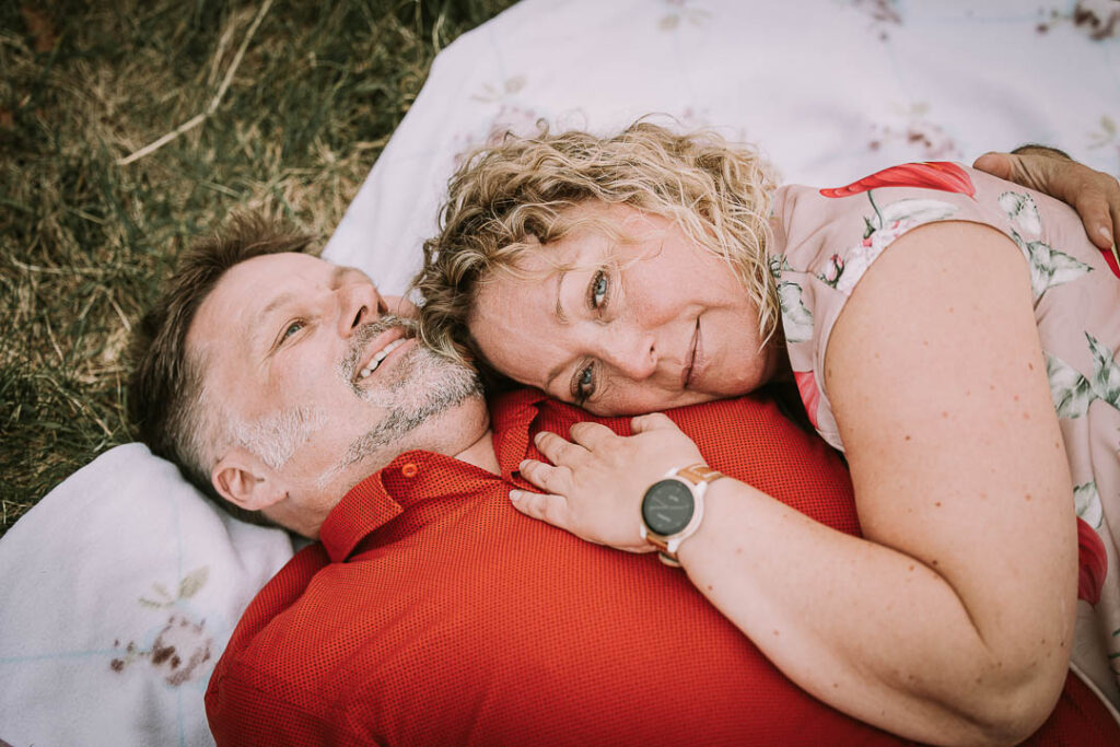 Udendørs parfotografering ved Hindsgavl Slot – par ligger i græsset.