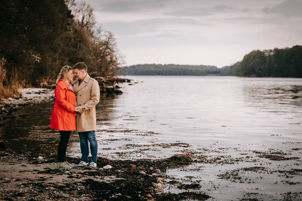 Parfotografering ved vandet ved Hindsgavl Slot – par går langs kysten.