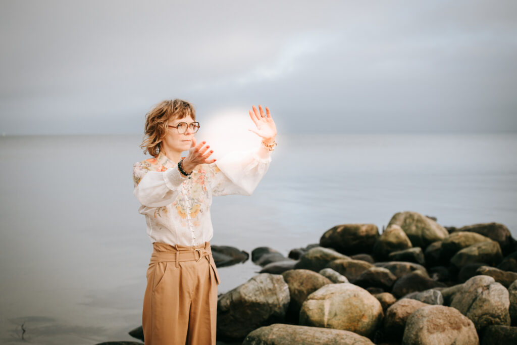 Auroura udfører energiarbejde på Østerstrand i Fredericia med havet som baggrund. Spirituel praksis i naturen.