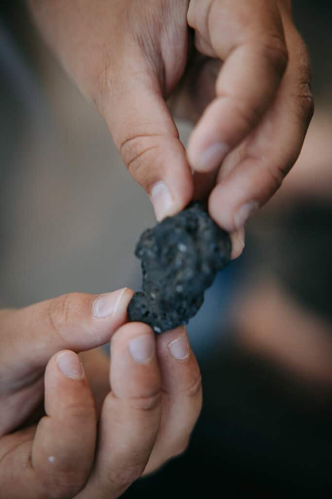 Hænder, der holder på mørk sten fundet ved kysten – autentisk familiefoto i Nordvestjylland.