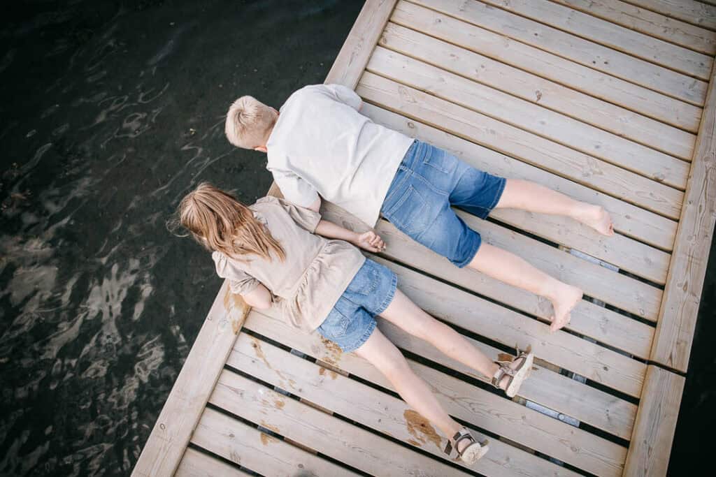 Familie ligger på badebro og nyder sommerdagen – autentisk familiefotografi i Nordvestjylland.