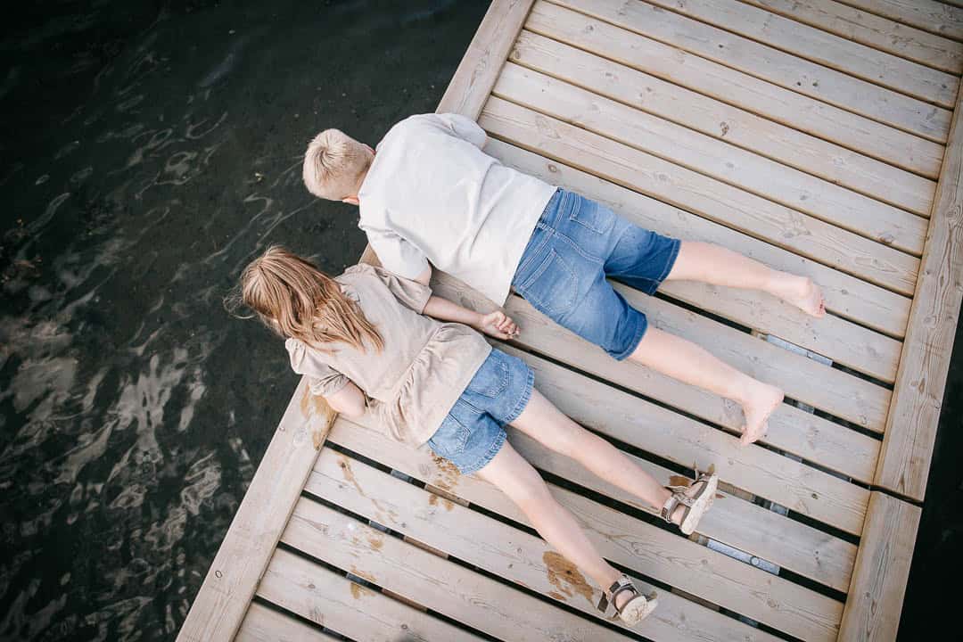 Familie ligger på badebro og nyder sommerdagen – autentisk familiefotografi i Nordvestjylland.