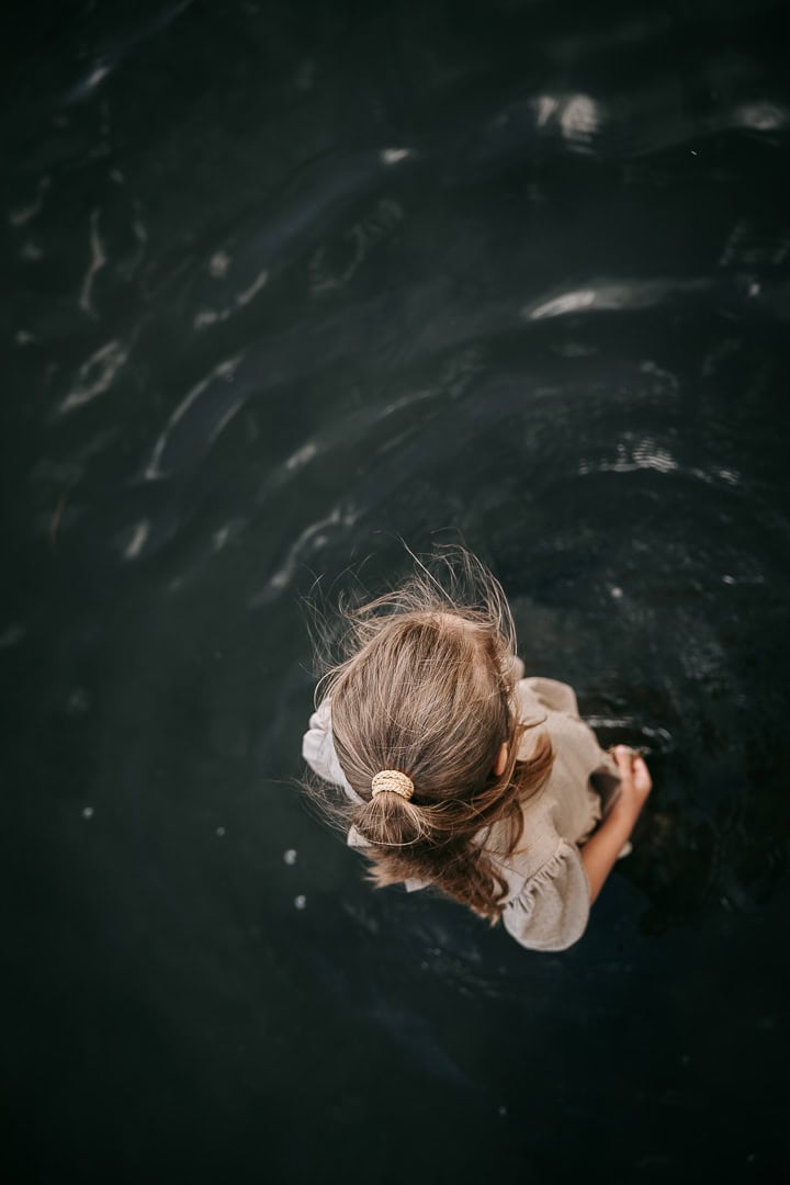 Barn svømmer i vandet set fra oven – autentisk børnefotografering ved stranden i Struer.
