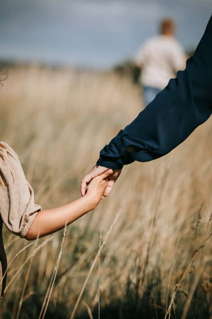Mor og datter holder i hånd i strandgræsset – familiefotograf Holstebro fanger varme øjeblikke.