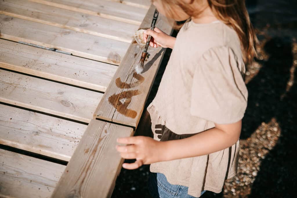 Barn sidder på badebro med fiskenet – familiefotograf Lemvig fanger sommerstemning.