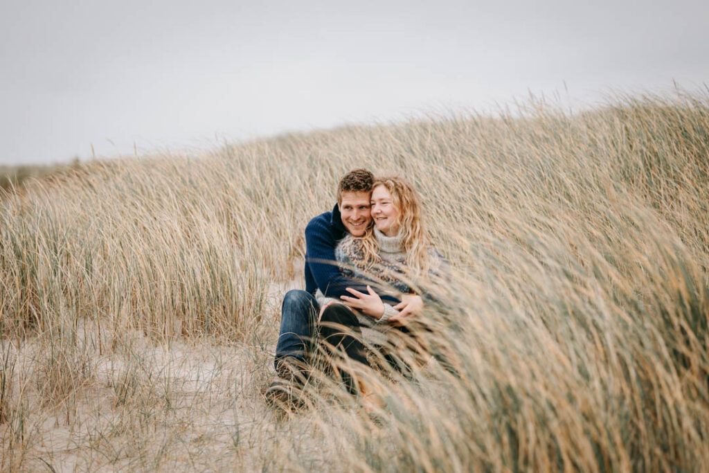 Kærligt blik mellem par omgivet af græs og sandklitter.