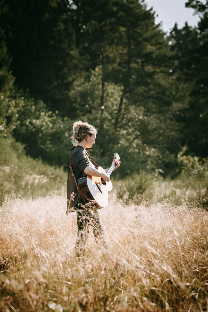 Kvinde står i mark med guitar – musik og lyd som helende kraft