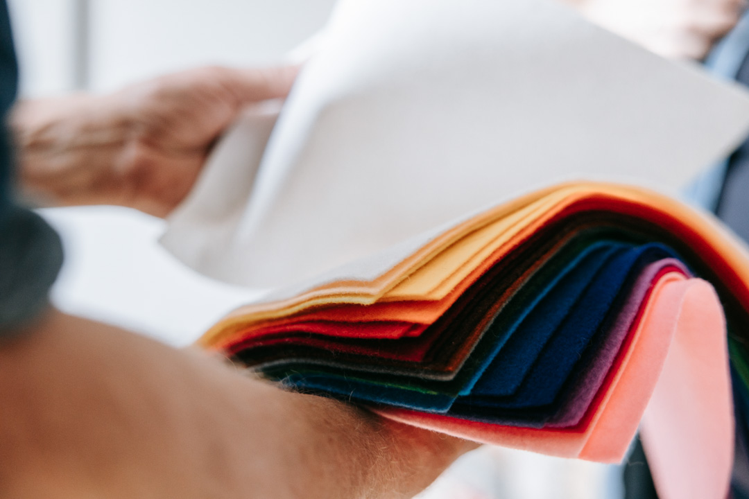 Hænder der holder farvede filtstykker brugt i terapeutisk arbejde.