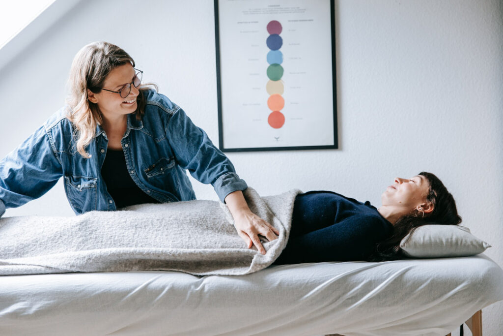 Terapeut lægger tæppe om klient på briks under behandling.