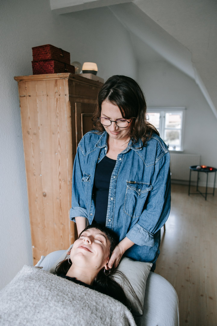 Terapeut giver blid støtte ved klientens hoved som del af kropslig behandling.