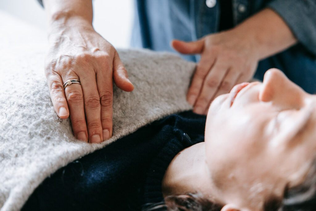 Terapeutens hænder placeret nær klientens krop som del af energetisk støtte.