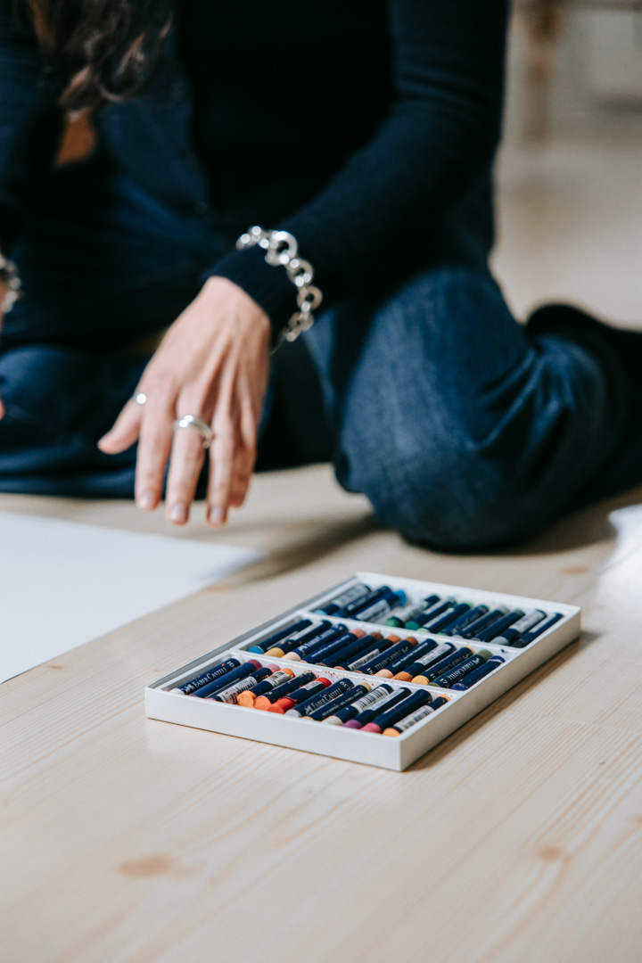 Klient sidder med farvekridt på gulvet i kreativ terapeutisk øvelse.