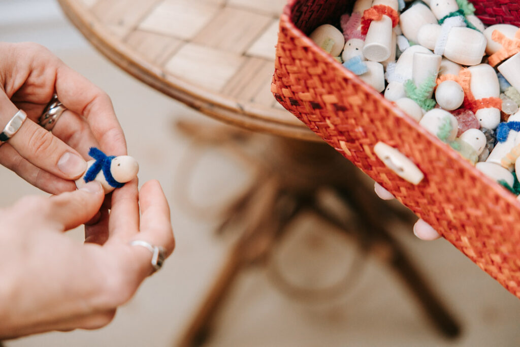 Hænder der holder små træfigurer brugt til terapeutiske samtaler.