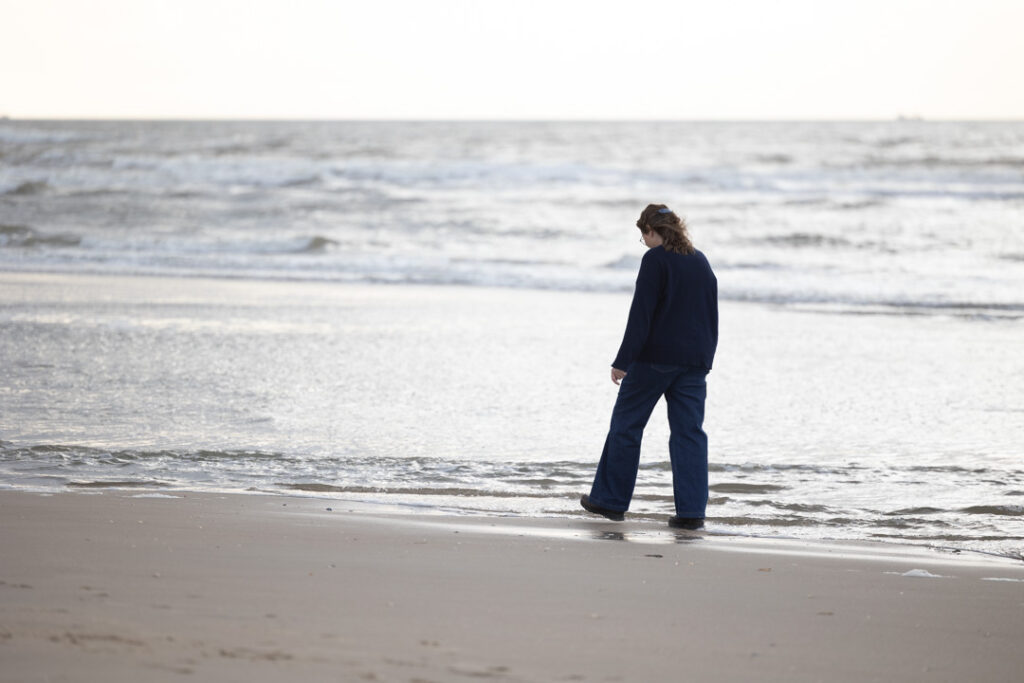 Terapeut går ved vandkanten på Rømø strand.