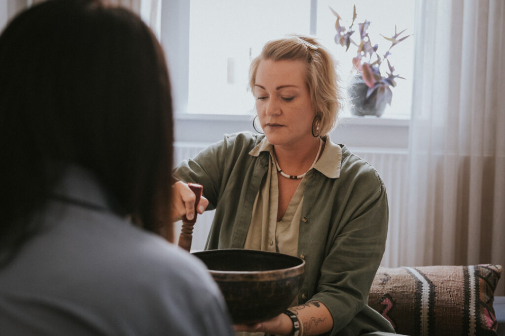 Gry Kok Ravn bruger en klangskål sammen med en kunde, fotograferet af Zoey Elinor.