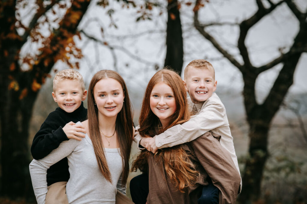 Søskende der krammer og smiler i naturen på en stille efterårsdag i Midtjylland