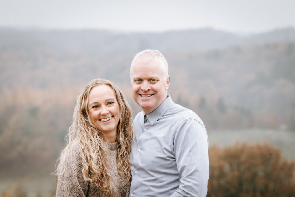 Ægtepar stående sammen i naturen med varme efterårsfarver omkring sig