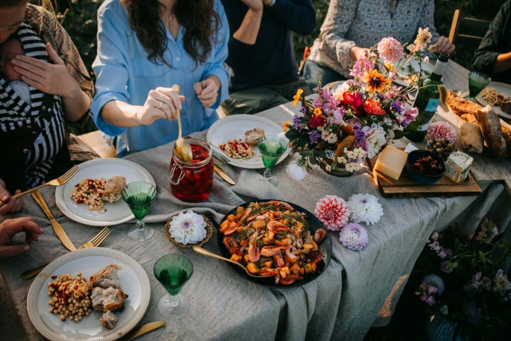 Eventfotograf dokumenterer deltagere samlet om et udendørs langbord.