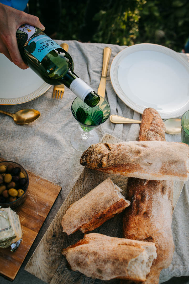 Eventfotograf fanger hånd der hælder vin op ved udendørs opdækning.
