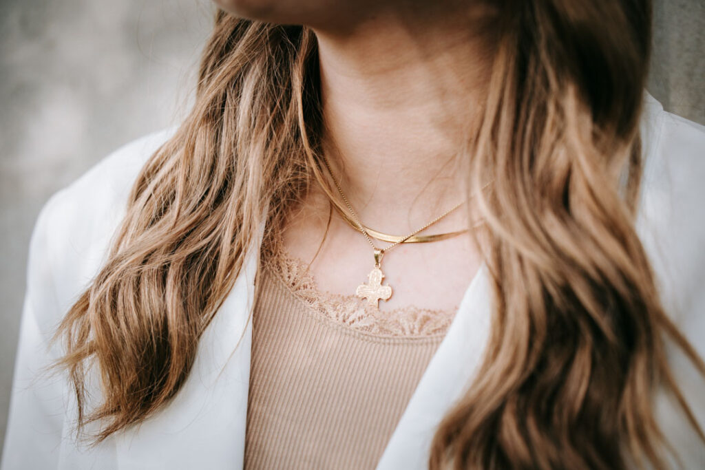 Detaljebillede af konfirmandens halskæde og tøj på konfirmationsdagen med fokus på materialer og stemning.