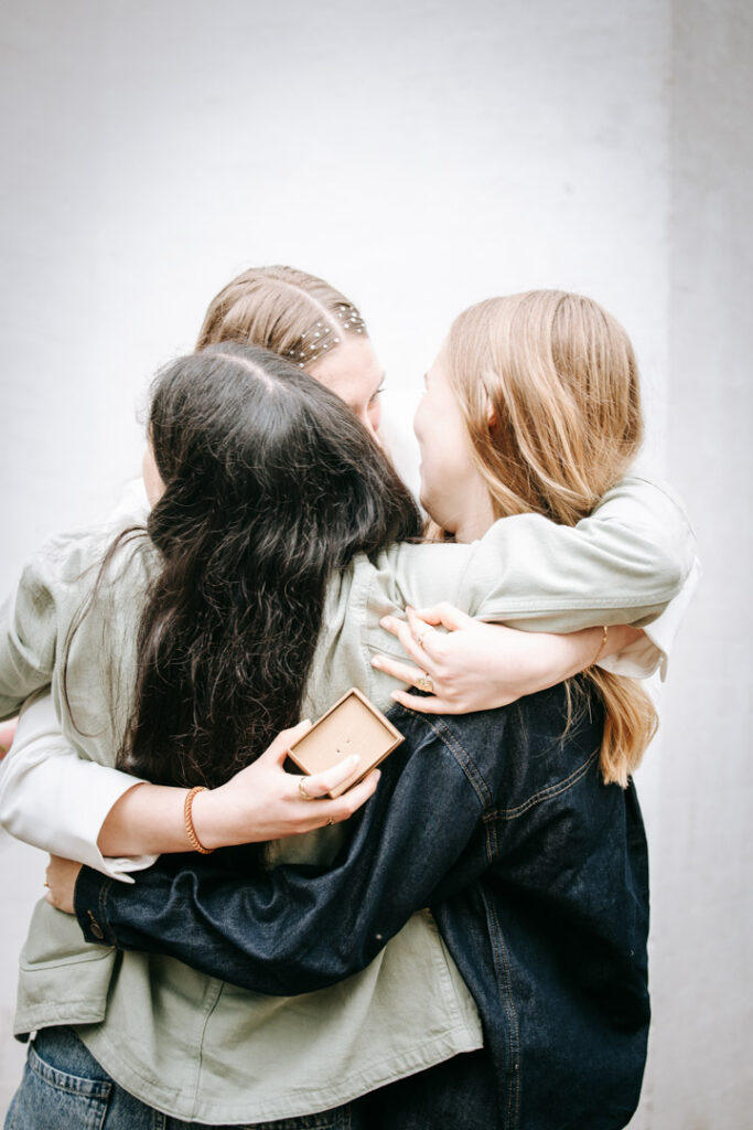 Konfirmand omfavner en nær relation udenfor kirken i et varmt og følelsesfuldt øjeblik.