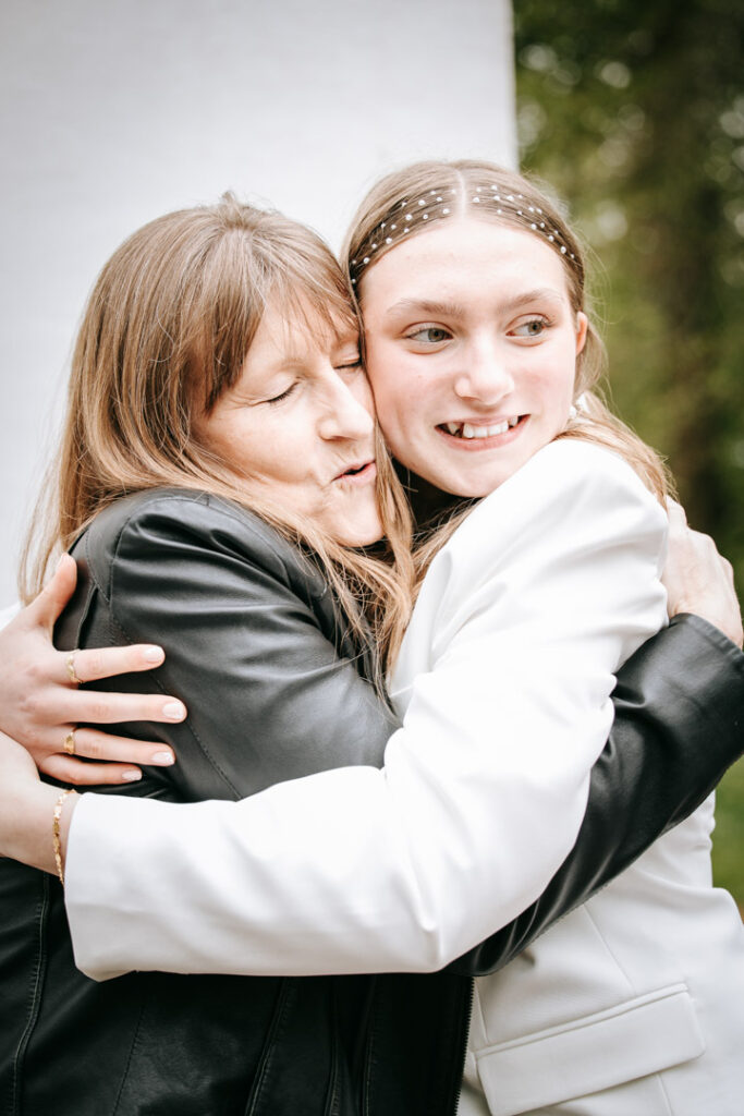 Tæt kram mellem konfirmand og familiemedlem fyldt med nærvær og glæde.